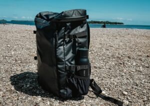 A durable gym bag for men sitting on the pavement against a clear blue sky backdrop.