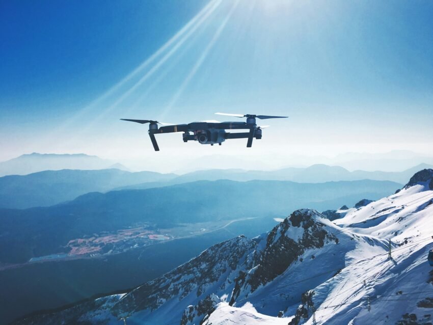 DJI drone with camera flying over snowy mountain peaks for follow me action sports
